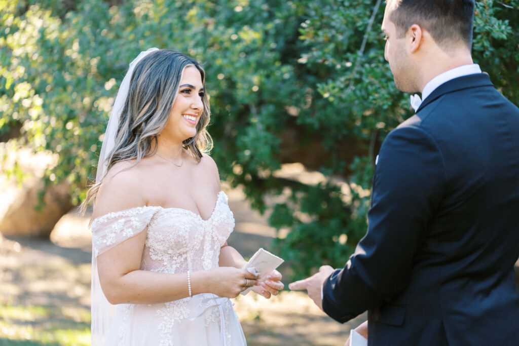 Bride smiles as Groom reads vows during First Look at Calamigos Ranch - Lisa Leanne Photography