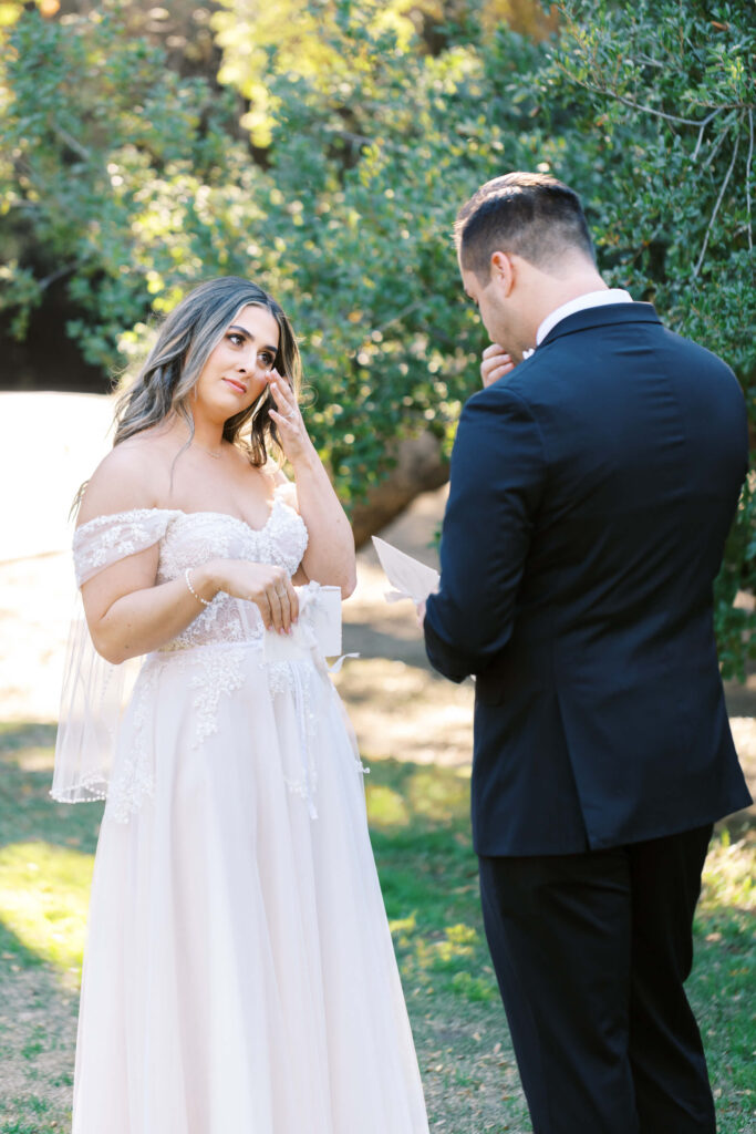 Bride wiping tear as Groom reads vows during First Look at Calamigos Ranch - Lisa Leanne Photography