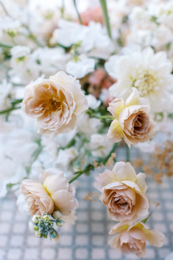 Calamigos Ranch Wedding Florals - A close-up of pale peach and cream roses and delicate white flowers arranged together, creating a soft, romantic floral display with a blurred background. Copyright - Lisa Leanne Photography, California